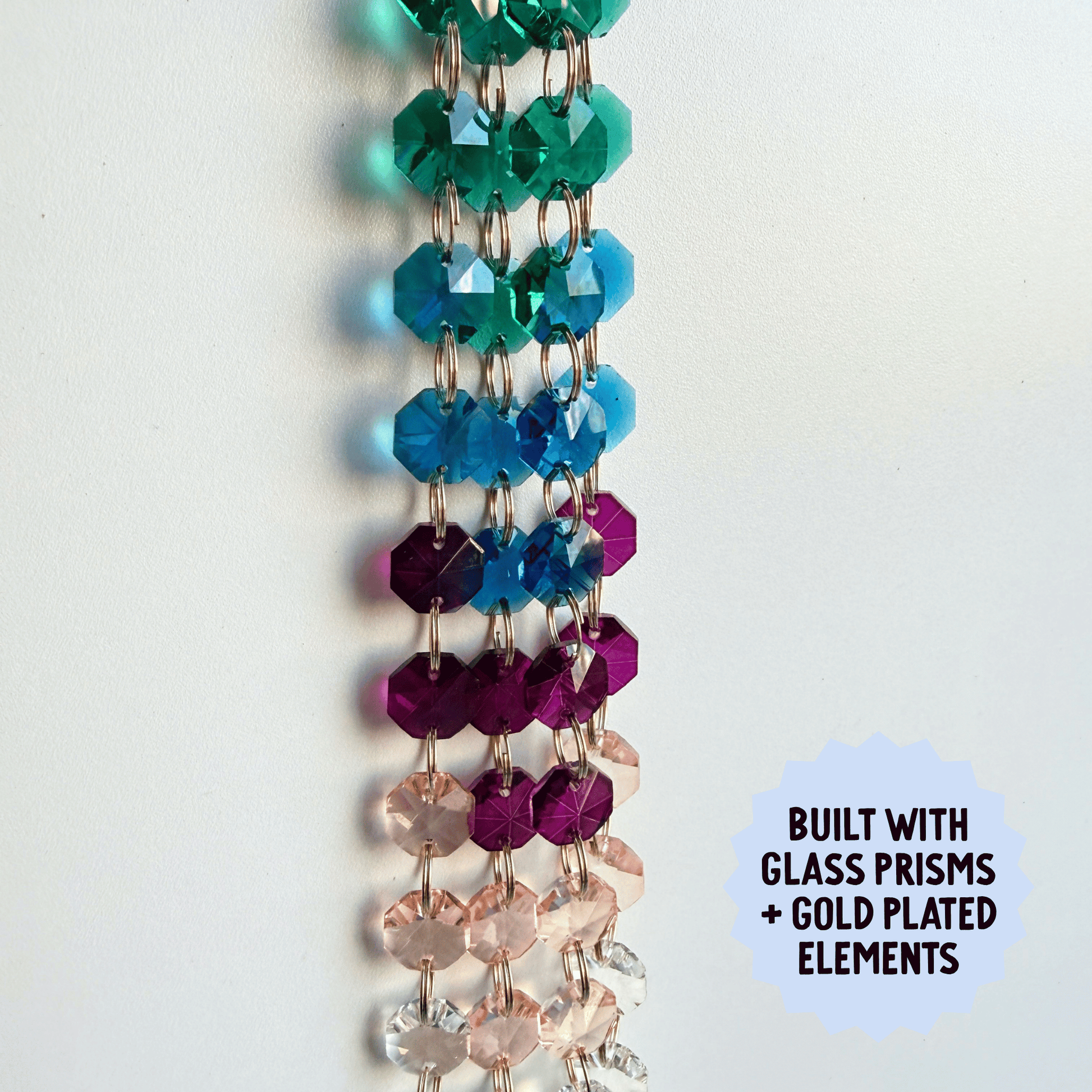 Colorful beaded suncatcher with glass prisms and gold plating on a white background